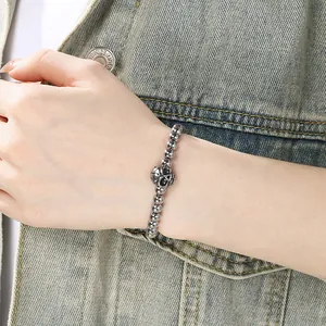 Close-up of stainless steel skull charm bead bracelet on wrist with denim jacket