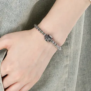 Close-up of stainless steel beaded bracelet with skull charm on a person's wrist