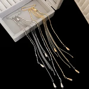 Elegant gold and silver metal chain tassel brooches with waterdrop pendants on black background