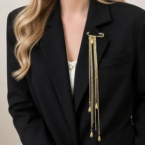 Elegant gold metal chain tassel brooch with teardrop charms pinned to a black blazer