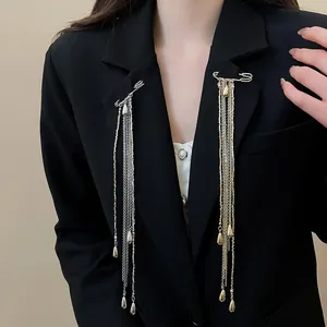 Detail of gold and silver safety pin brooches with long metal chain tassels