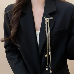 Detailed view of elegant gold tassel brooch with long chain fringe on black blazer