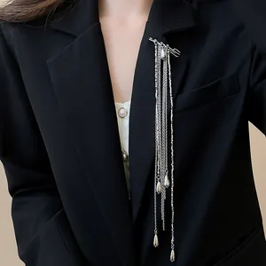 Close-up of a silver multi-layer chain tassel brooch worn on a black blazer jacket