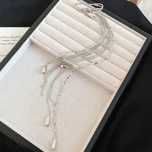 Close-up of silver metal chain tassel brooch with teardrop charms on jewelry tray