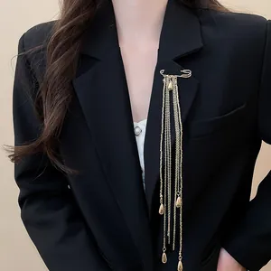 Detailed view of an elegant gold metal chain tassel brooch pinned on a black blazer
