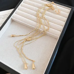 Detailed view of a gold-toned multi-strand metal chain tassel brooch with teardrop charms.
