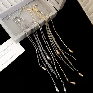 Detail of gold and silver long tassel brooches with metal chains and teardrop charms