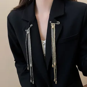 Close-up of gold and silver metal chain tassel brooches pinned on a black blazer