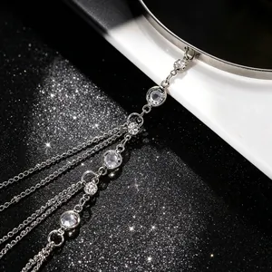 Detail van zilveren bovenarmband met gelaagde kristallen kwastjes op glitter achtergrond