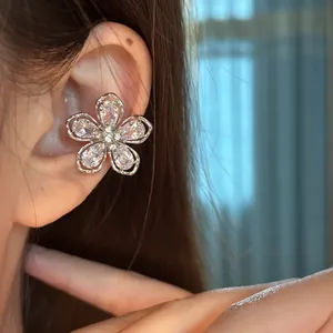 Gros plan d'un clip d'oreille étincelant en forme de fleur en zircone sur l'oreille.