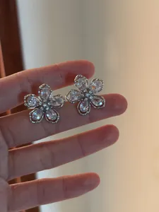 Gros plan détaillé de boucles d'oreilles fleurs en argent avec pierres en zircone cubique.
