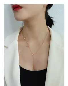 Detail shot of 18k gold plated LOVE letter necklace on model wearing white suit