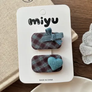 Détail de barrettes à carreaux avec nœud en velours bleu et cœur tissé sur la carte