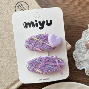 Détail de barrettes en tweed violet avec cœur 3D et nœud ruban sur carte de support