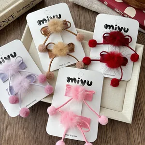 Gros plan de barrettes à nœuds et pompons en peluche de quatre couleurs sur un plateau