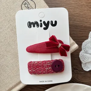 Vue détaillée de barrettes à cheveux en velours rouge et tweed sur carte blanche
