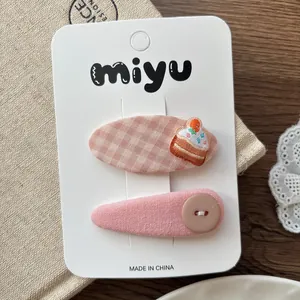Détail de barrettes roses à carreaux avec broderie cupcake et bouton pour fille