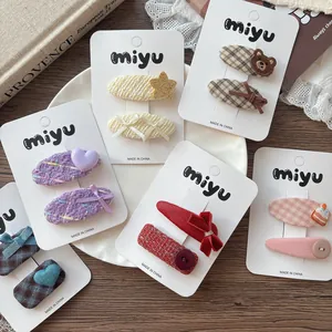 Détail de barrettes pour enfants avec motifs à carreaux et breloques mignonnes cœur et ours