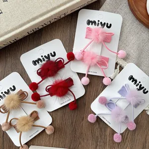Détail de pinces à cheveux avec nœuds et pompons en peluche en quatre couleurs douces