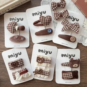 Detailed set of brown plaid bow hair clips with heart and bear embroidery on cards