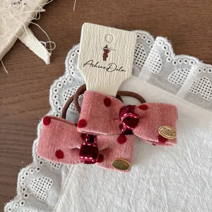 Dettaglio di elastici per capelli in velluto rosa a pois con logo dorato e pizzo