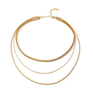 Détail d'un collier triple couche en acier inoxydable doré avec maillons boîte et serpent.