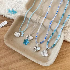 Dettaglio di collane di perline blu con ciondoli a conchiglia e stella marina.