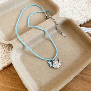 Dettaglio della collana di perline blu con ciondolo a conchiglia e stella