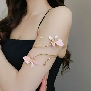 Vista detallada de brazalete vintage dorado con flores de esmalte rosa en el brazo