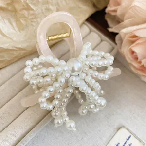Detail view of a sweet pearl bow hair claw clip featuring a pink resin base and elegant finish.