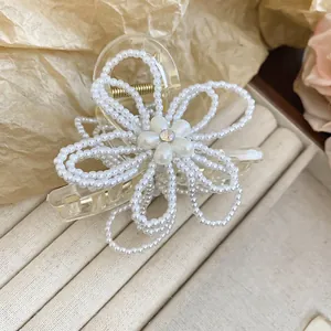 Detailed view of elegant white pearl flower hair claw clip on jewelry tray