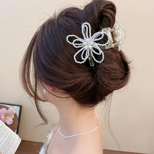 Detailed view of an elegant pearl flower hair claw clip worn on a bun hairstyle.