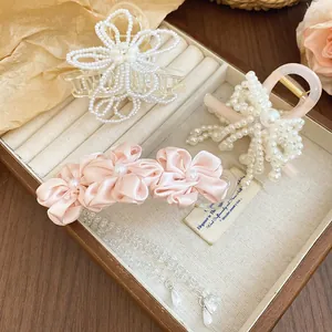 Detailed view of elegant pearl flower and pink ribbon bow hair clips in a jewelry box