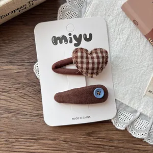 Close-up of brown fabric hair clips with heart patterns and small button detail