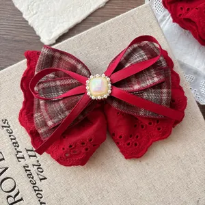 Close-up of layers including red lace, plaid fabric, and pearl gemstone on a hair clip