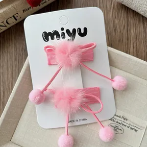 Détail de barrettes à nœuds en velours rose avec pompons doux sur présentoir