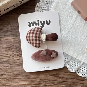 Detail of checkered mushroom and floral velvet hair clips on a white display card