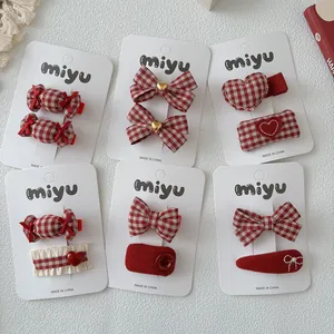 Detail van rood en wit geblokte strik haarspeldjes voor meisjes op een witte kaart