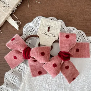 Dettaglio di elastici per capelli a pois rosa con nodi in velluto su sfondo di legno