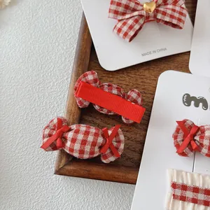 Rood-wit geblokte strikjes haarspeldjes met gouden hartjes op een displaykaart