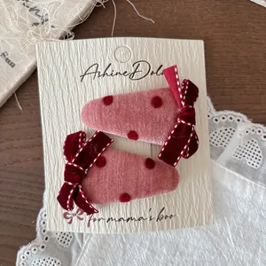 Dettaglio di fermagli per capelli a fragola rosa con pois rossi e fiocco in velluto