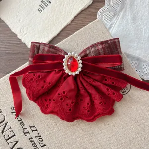 Detail of red lace bow hair clip with velvet ribbon and pearl-encrusted red gemstone