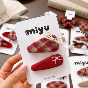 Set of two red plaid hair clips with bow details for girls shown on display card