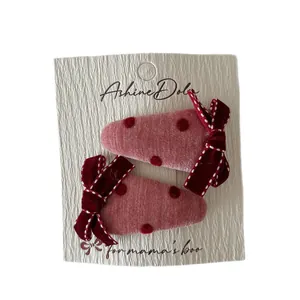 Fermagli rosa a pois con fiocchi in velluto rosso scuro su cartoncino bianco