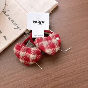 Close-up of heart-shaped plaid hair ties with bead trim on a wooden background