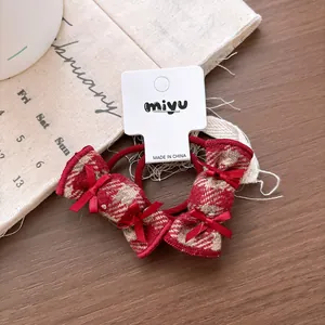 Detail of red plaid fabric hair ties with ribbon bows on a display card for girls