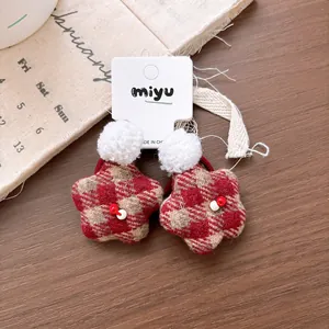 Detail of red plaid star hair ties with white pom-poms on a rustic wooden background
