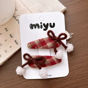 Detail of red and brown plaid hair clips with knitted bows and plush pom poms
