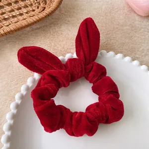 Detail shot of a dark red velvet scrunchie with rabbit ear bow on a ceramic plate