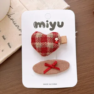 Close-up of red plaid heart and bow hair clips set on a decorative white card